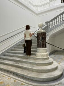 A visitor on the monumental marble staircase inside Palazzo Marignoli in Rome