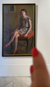 Painting of a seated figure by Gino Galli, partially obscured by a hand